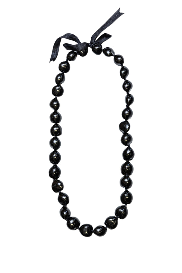 A black kukui nut lei with a smooth, glossy finish, tied together with a black ribbon.