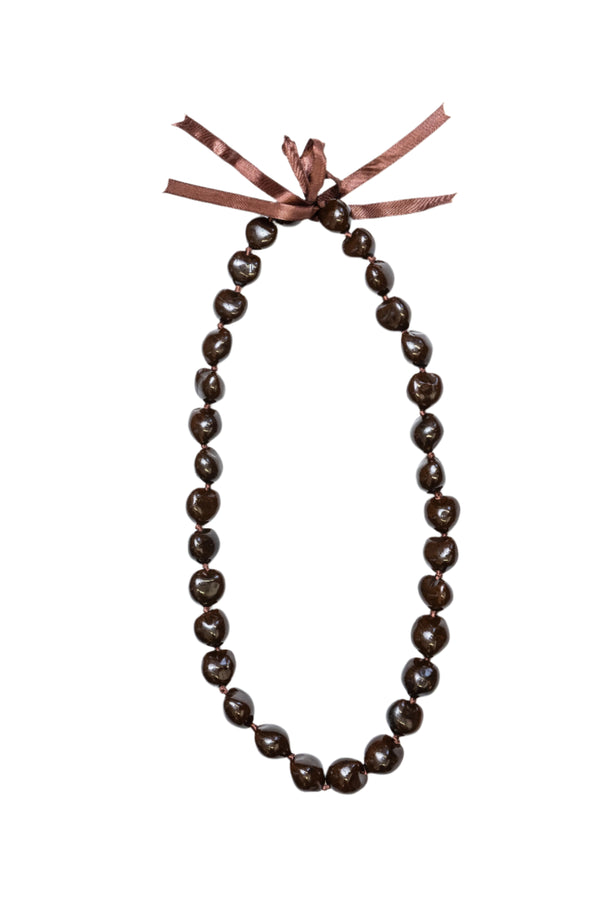A brown kukui nut lei with a smooth, glossy finish, tied together at the top with a brown ribbon.