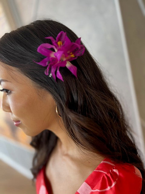 Girl with long hair wearing a fuchsia orchid hair clip.