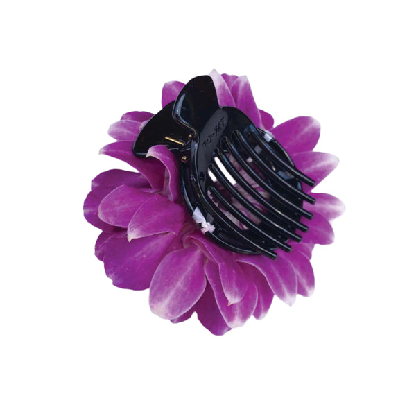 Black hair comb on a purple orchid petal flower with a white background.