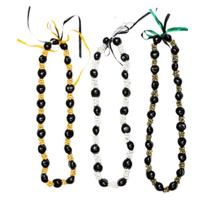 Collection of three leis featuring alternating patterns of glossy black Kukui nuts and Mongo shells in natural yellow, white, and green tones, tied with yellow, black, and green ribbons.