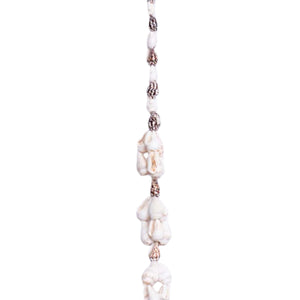 A lei made of various natural seashells, with a mix of small patterned shells and larger white shells.