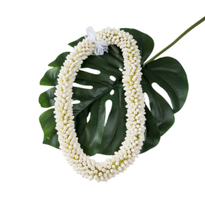 Faux double paper bud pikake lei with a white bow, displayed on a green monstera leaf.