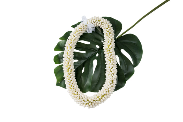 Faux double paper bud pikake lei with a white bow, displayed on a green monstera leaf.