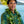 Man wearing a fresh Big Island Hilo-style maile lei with Diamond Head, a palm tree, and the ocean in the background.