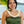 A woman wearing a green dress and a traditional micro ginger lei, ideal for weddings, with a background of a tropical setting.