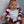 Baby leaning on a pillow, wearing a deep purple and white orchid lei.