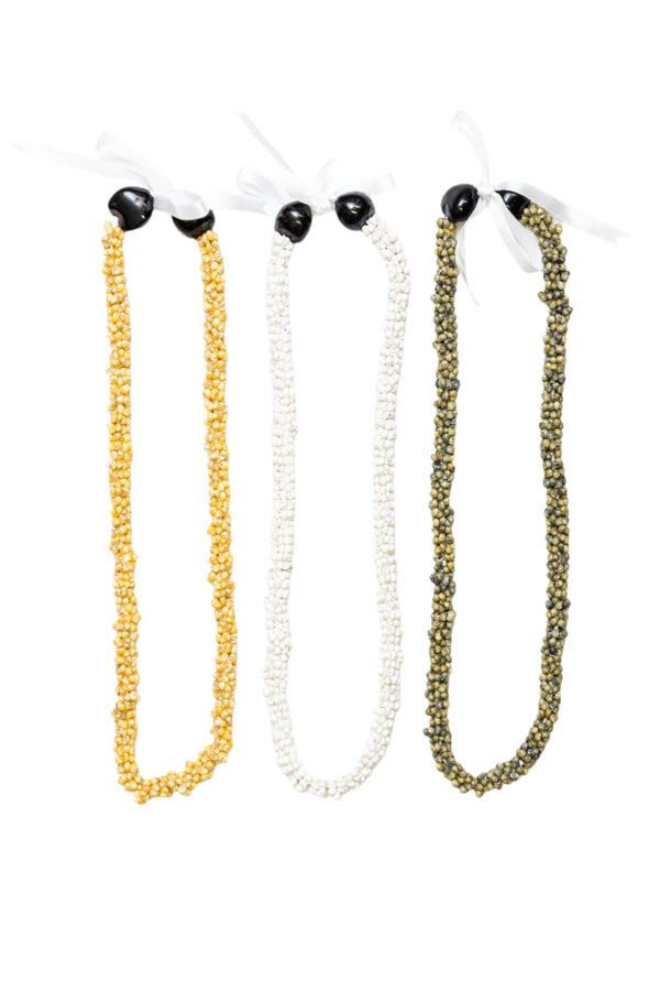 Collection of three leis made from mongo shells in pure yellow, white, and green, each adorned with two Kukui nuts and tied with a ribbon at the end.