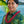 Man wearing a pure red cigar flower lei with Diamond Head, a palm tree, and the ocean in the background.
