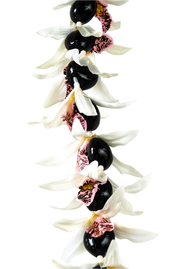 Close-up of a lei featuring silk white orchids with pink centers and glossy black kukui nuts, set against a white background.