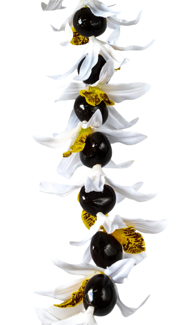 Close-up of a lei featuring silk white orchids with yellow centers and glossy black kukui nuts, set against a white background.