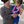 Elderly woman holding a young girl wearing a kid-size single strand purple orchid lei, with the beach in the background.