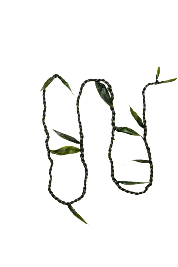 Single ti leaf lei twisted like a rope, with extra leaves protruding at intervals along the length.