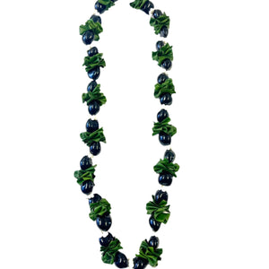 Ti leaf kukui nut lei featuring folded green ti leaves mixed with glossy black kukui nuts and white mongo shells, displayed on a white background.