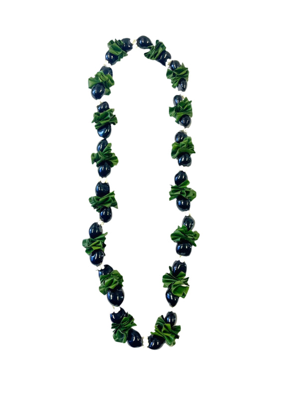 Ti leaf kukui nut lei featuring folded green ti leaves mixed with glossy black kukui nuts and white mongo shells, displayed on a white background.